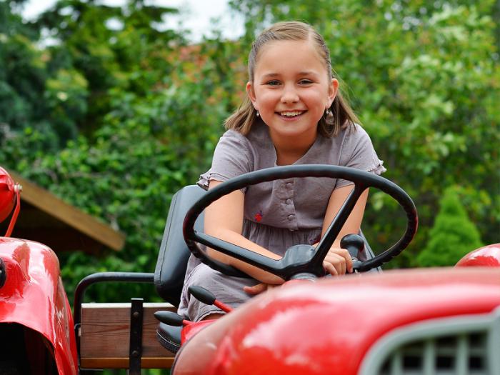 Mädchen sitzt auf rotem Traktor